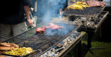 Imagen de várias barbacoas de carbón y leña en uso, se ve como están cocinando carne y la ceniza que esta quedando en la parte del fuego.