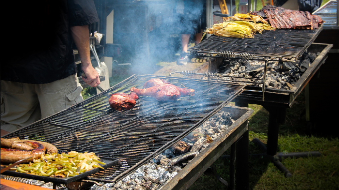 Imagen de várias barbacoas de carbón y leña en uso, se ve como están cocinando carne y la ceniza que esta quedando en la parte del fuego.