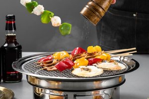 Parrillada de verduras en una barbacoa sin humo, se ve como están salpimentando las verduras y como retiran un pincho.
